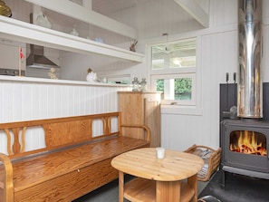 A cozy room with a wooden bench, a round table, a stove, and shelves with kitchenware. - 4 Person Holiday Home in Praesto (Praesto)