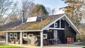 A house with a covered patio, a barbecue, and a bicycle. - 4 Person Holiday Home in Praesto (Praesto)