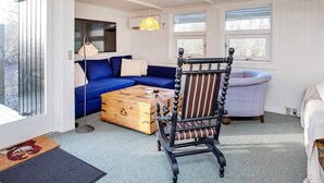 A cozy room with a blue sofa, a wooden chest, a vintage chair, and a lamp. - 4 Person Holiday Home in Praesto (Praesto)