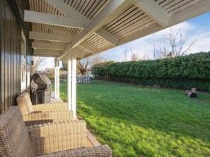 A covered outdoor seating area with wicker furniture, a barbecue grill, and a well-maintained lawn. - 4 Person Holiday Home in Praesto (Praesto)