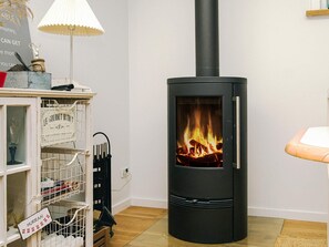 A modern room with a black wood-burning stove, a white shelf unit, and a lamp.