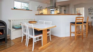 A cozy kitchen with a dining table, white chairs, a built-in stove, and a hanging light fixture. - Simplistic Holiday Home in GÃ¸rlev near Sea (Gørlev)
