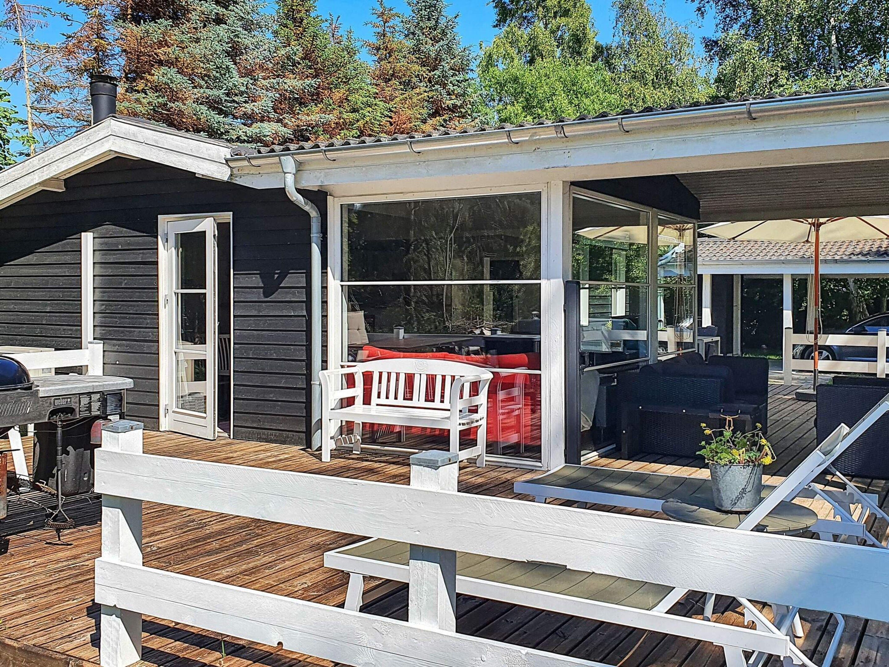 A wooden deck with outdoor furniture, a grill, and a covered patio area.