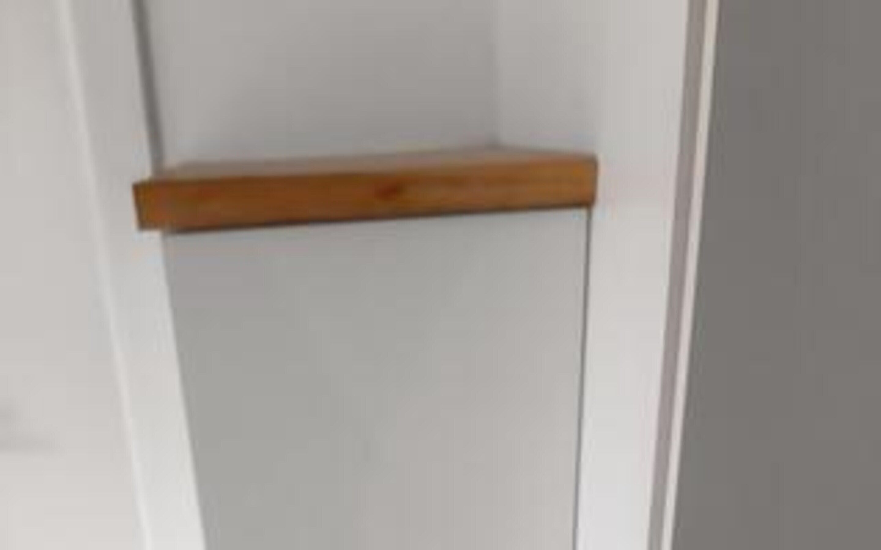 Una puerta blanca con un estante de madera.