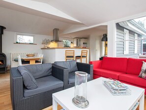 A cozy living area with a fireplace, a red sofa, and a white coffee table. - Simplistic Holiday Home in GÃ¸rlev near Sea (Gørlev)