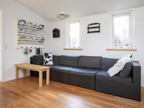 A living room with a grey sofa, a wooden table, and a wall-mounted dish rack. - Simplistic Holiday Home in GÃ¸rlev near Sea (Gørlev)
