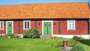 Ein rotes Gebäude mit Ziegeldach, grünen Türen und weißen Fensterrahmen.