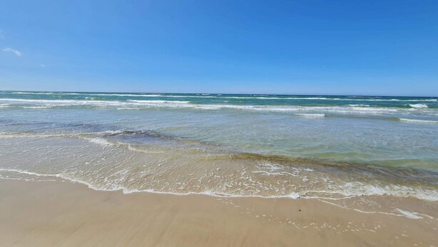 A beach with clear blue water and a sandy shore. - 6 Person Holiday Home in Brovst (Brovst)