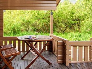 A wooden deck with a table and chairs, overlooking a lush green landscape. - Captivating Holiday Home in RingkÃ¸bing near Sea (Ringkobing)