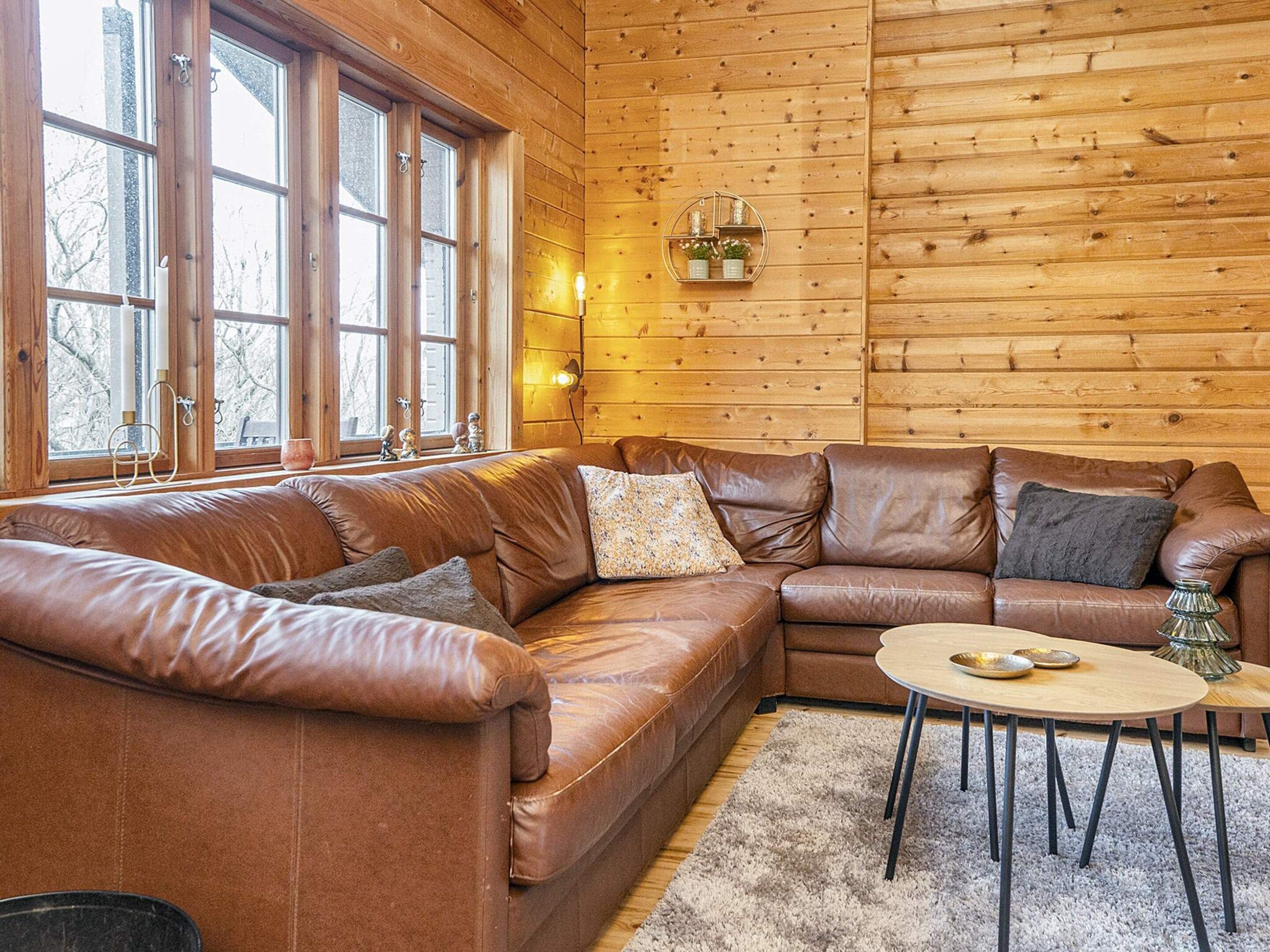 A cozy living room with a brown leather sectional sofa, a round coffee table, and a fireplace.