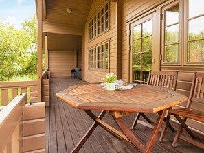 A wooden deck with a table and chairs, surrounded by a wooden fence, and large windows. - Captivating Holiday Home in RingkÃ¸bing near Sea (Ringkobing)
