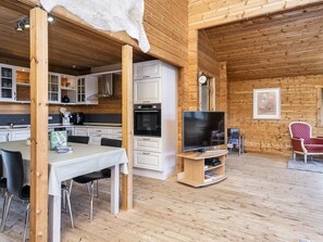 A wooden interior with a dining table, chairs, a flat-screen TV, and a red chair.