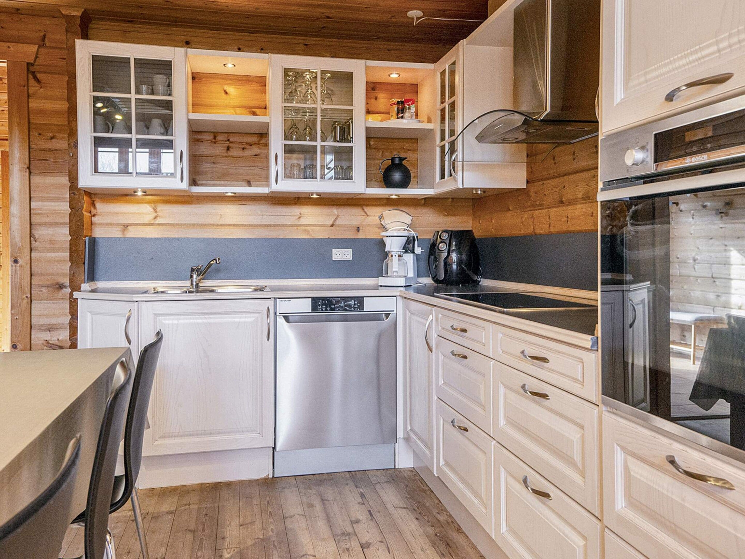 A compact kitchen with white cabinetry, a dishwasher, a coffee maker, and a stove.