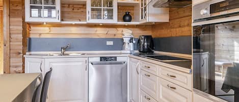 A compact kitchen with white cabinetry, a dishwasher, a coffee maker, and a stove.