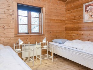 A cabin room with wooden walls, a window, a bed, a desk with two lamps, and a painting on the wall. - Captivating Holiday Home in RingkÃ¸bing near Sea (Ringkobing)