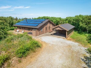 A wooden cabin with a gravel driveway and a covered porch. - Captivating Holiday Home in RingkÃ¸bing near Sea (Ringkobing)