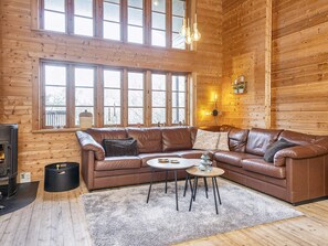 A cozy cabin interior with a brown leather sofa, a small round table, and a fireplace. - Captivating Holiday Home in RingkÃ¸bing near Sea (Ringkobing)
