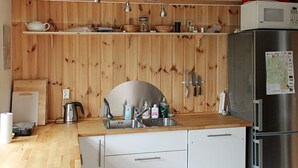 A modern kitchen with wooden panel walls, a stainless steel refrigerator, and a wooden countertop.