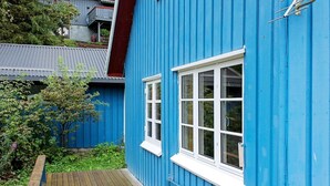 A blue building with a wooden deck and a window.