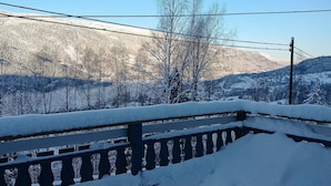 A snow-covered balcony with a view of a mountainous landscape.