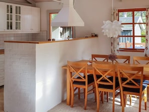 A kitchen with white cabinets, a wooden island, and a dining area with wooden chairs and a table.