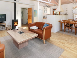 A cozy living room with a sofa, a coffee table, a fireplace, and a dining area with a table and chairs.