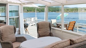 A covered outdoor seating area with wicker furniture, a table, and a view of a lake. - 6 Person Holiday Home in Brevik (Porsgrunn)