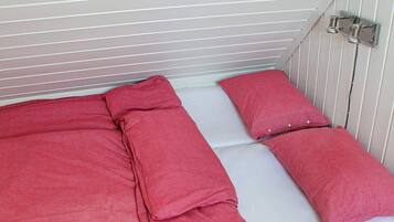A single-bed room with a white mattress and red bedding.