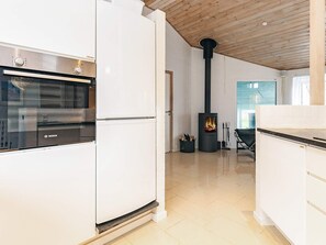 A modern kitchen with white cabinetry, a Bosch oven, and a wood-burning stove. - 5 Star Holiday Home in Hjorring (Hjørring)