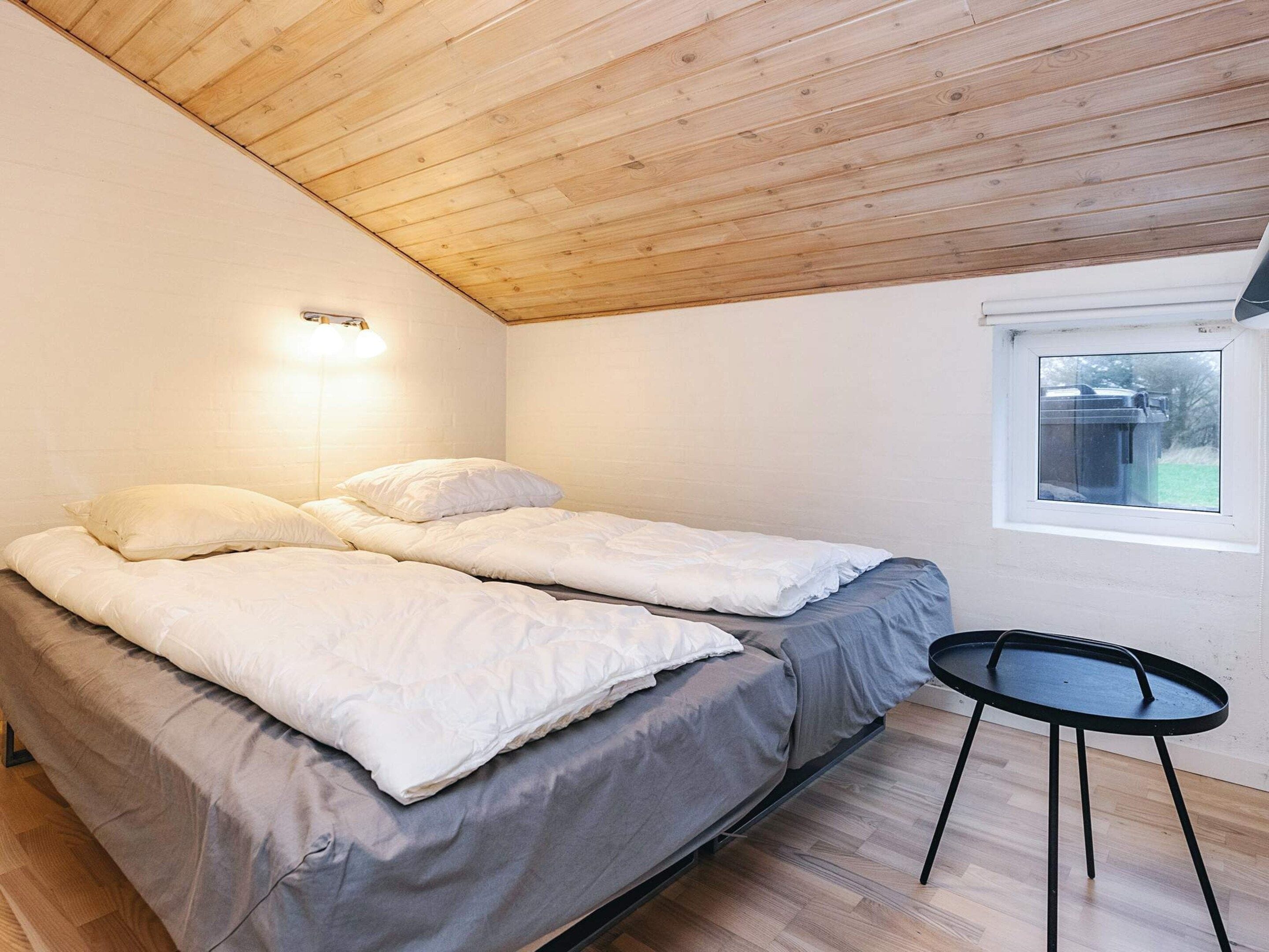 Une chambre avec deux lits, une petite table ronde et une fenêtre.
