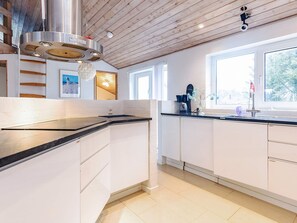 A modern kitchen with white cabinets, a stainless steel range hood, and a window providing natural light. - 5 Star Holiday Home in Hjorring (Hjørring)