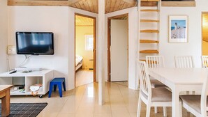 A modern, well-lit room with a wooden ceiling, a flat-screen TV, a dining table with chairs, and a staircase. - 5 Star Holiday Home in Hjorring (Hjørring)