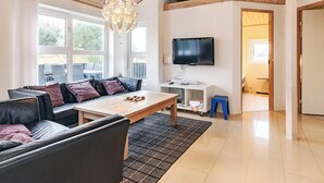 A modern living room with a wooden ceiling, a black leather sofa, a wooden coffee table, and a television on the wall. - 5 Star Holiday Home in Hjorring (Hjørring)