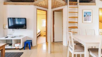 A room with a TV, a desk, a chair, a dining table, and a ladder.