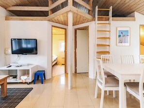 A room with a TV, a desk, a chair, a dining table, and a ladder. - 5 Star Holiday Home in Hjorring (Hjørring)
