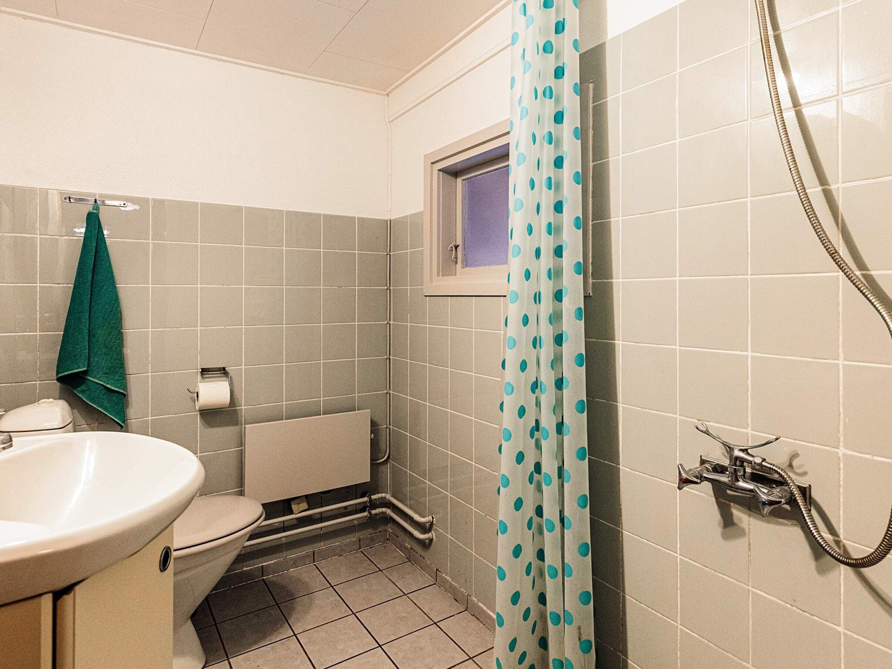 Et lille badeværelse med toilet, vask og brusebad.