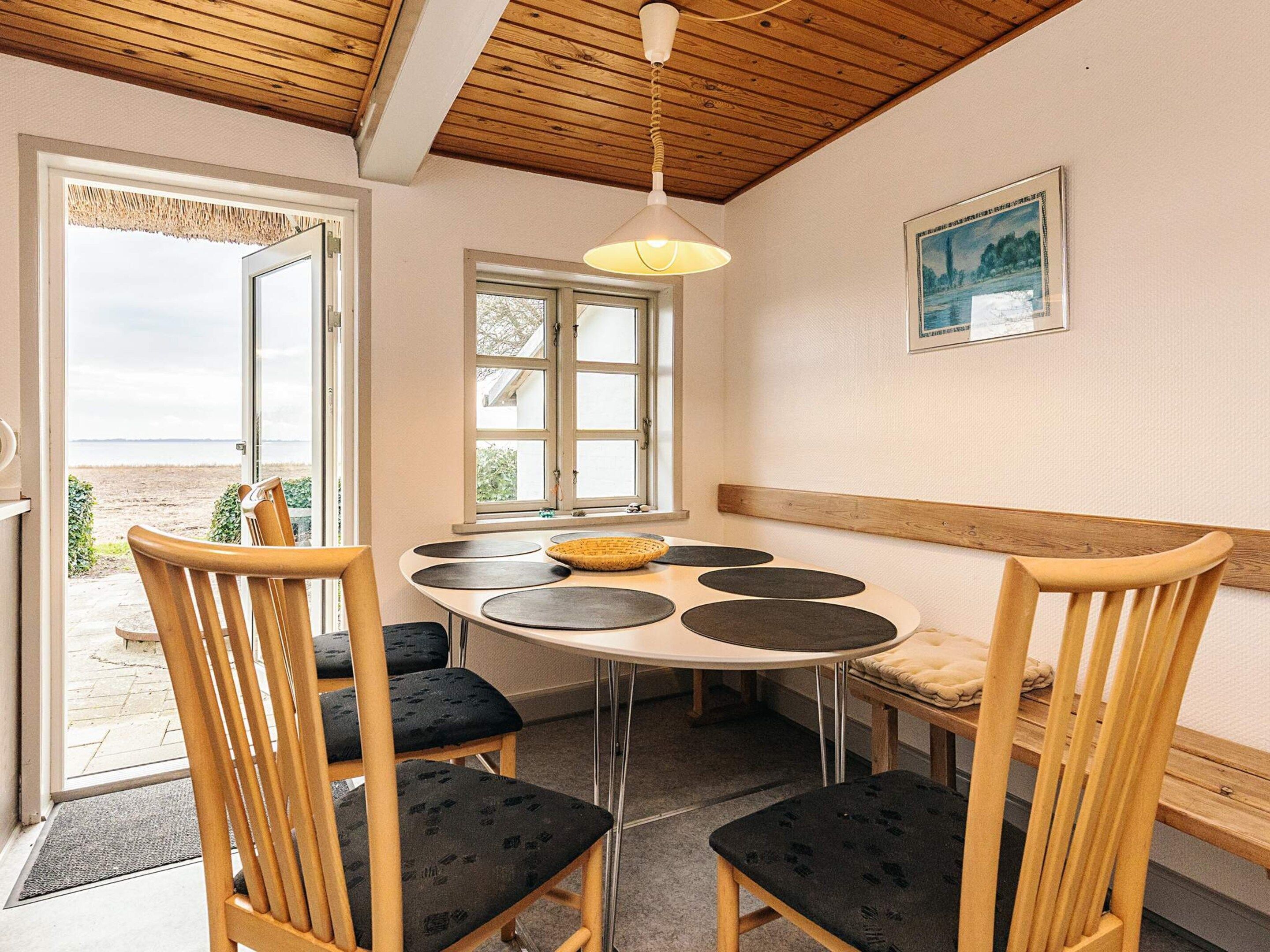 A dining area with a round table, six chairs, and a hanging light fixture.