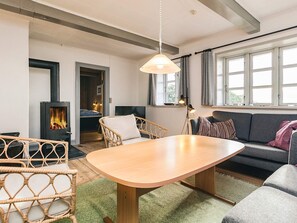 A cozy living room with a wooden dining table, wicker chairs, a sofa, and a fireplace. - 8 Person Holiday Home in Svendborg (Svendborg)