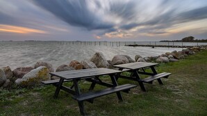 A beach with picnic tables and a wooden pier extending into the water. - 8 Person Holiday Home in Svendborg (Svendborg)