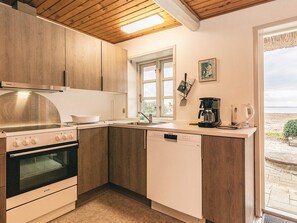 A kitchen with wooden cabinets, a stove, a dishwasher, and a coffee maker. - 8 Person Holiday Home in Svendborg (Svendborg)