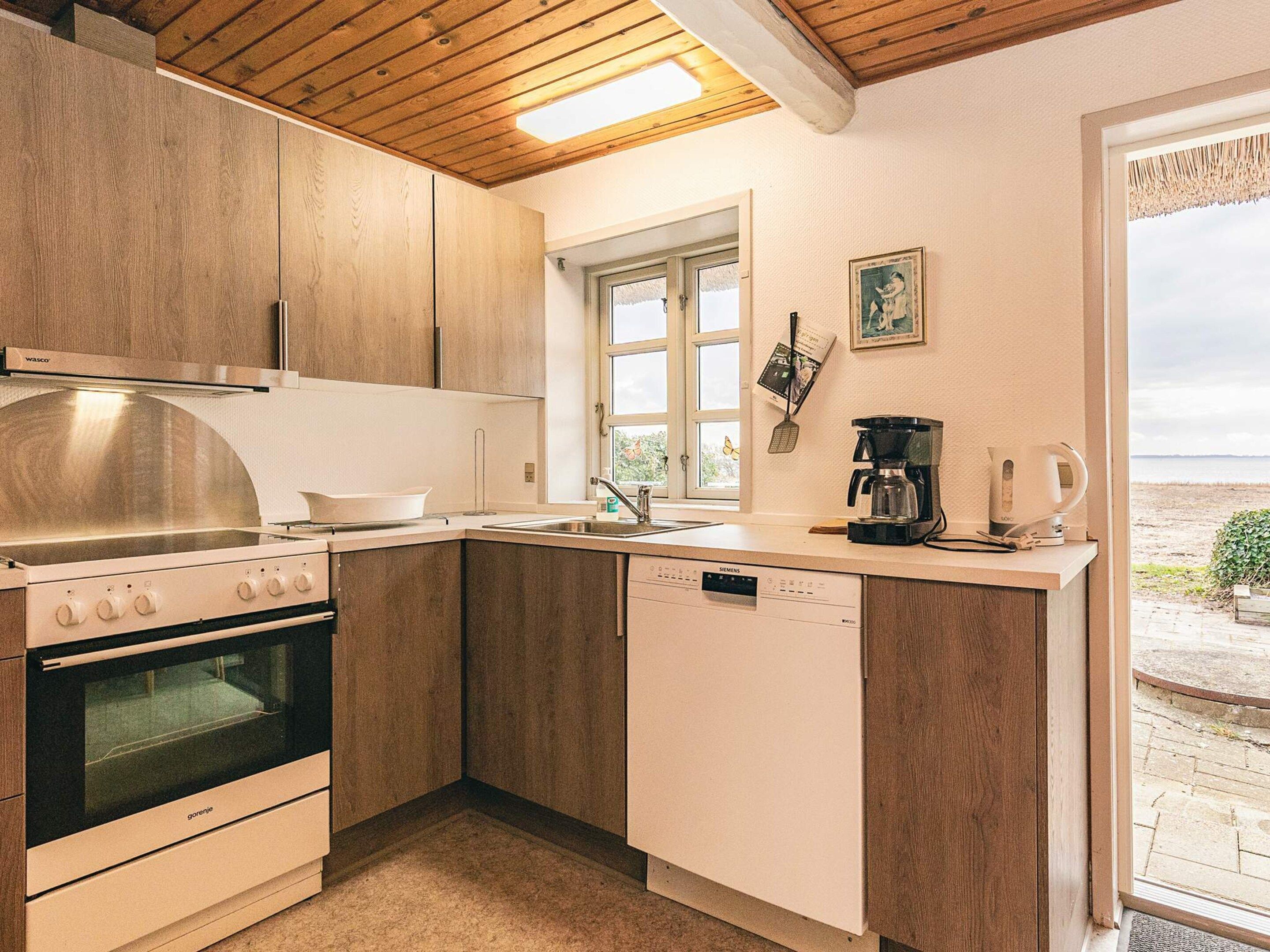 A compact kitchen with wooden cabinets, a built-in oven, and a dishwasher.