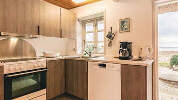 A compact kitchen with wooden cabinets, a built-in oven, and a dishwasher.