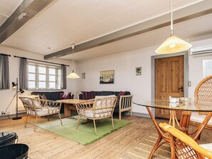 Un salon chaleureux avec un canapé, une table à manger et des chaises, un tapis vert et un plancher en bois.
