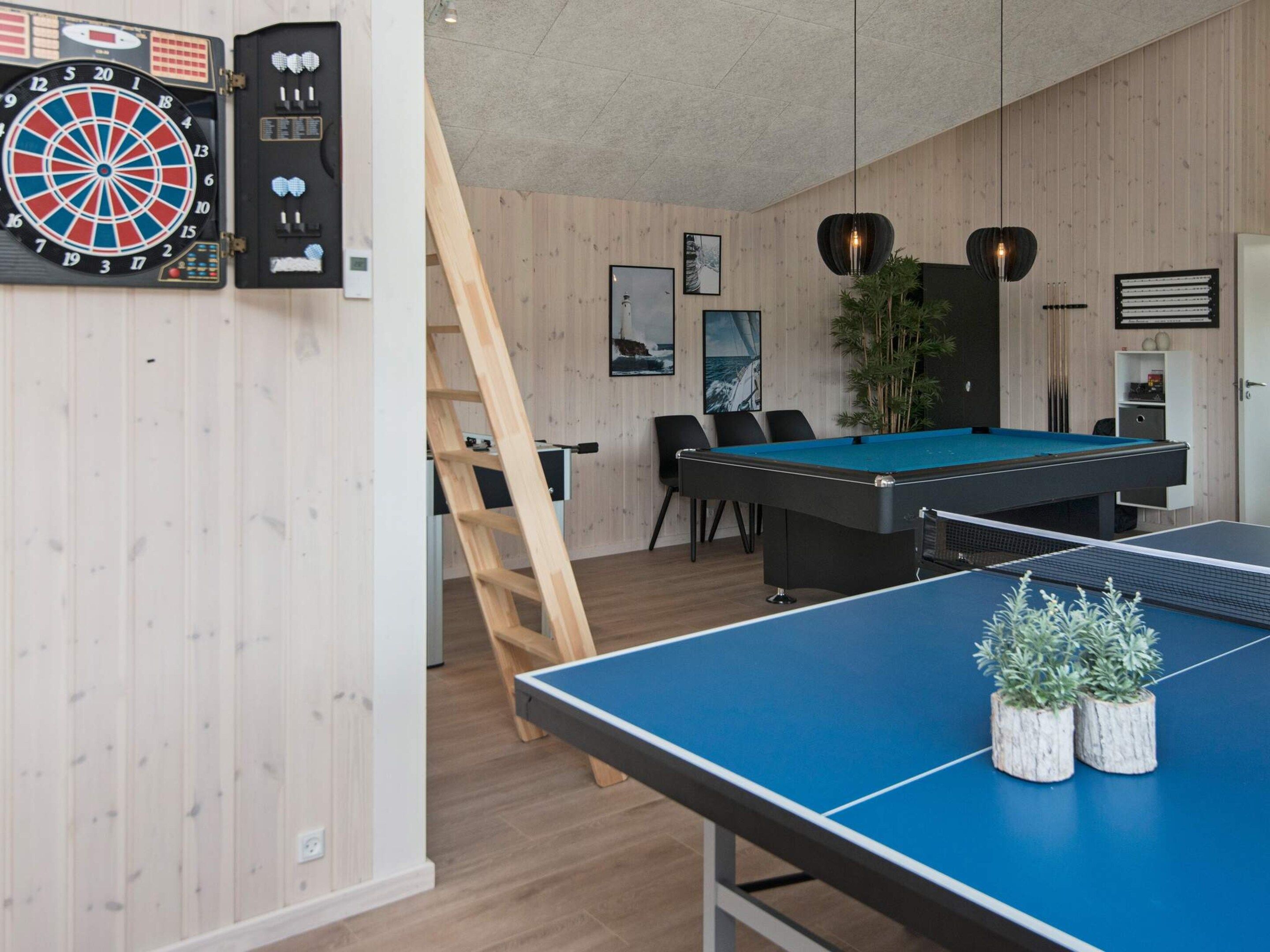 Een kamer met een dartbord, een pooltafel en een pingpongtafel.