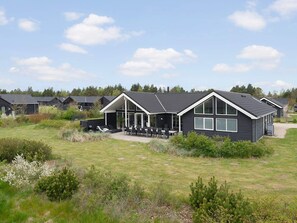Een modern huis met een terras, omgeven door een gazon en andere vergelijkbare woningen.