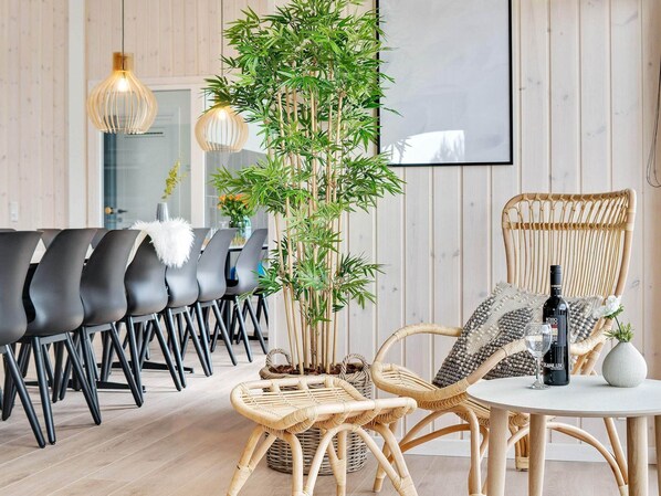Uma sala de jantar moderna com cadeiras pretas, uma mesa redonda, cadeiras de vime e uma planta de bambu.
