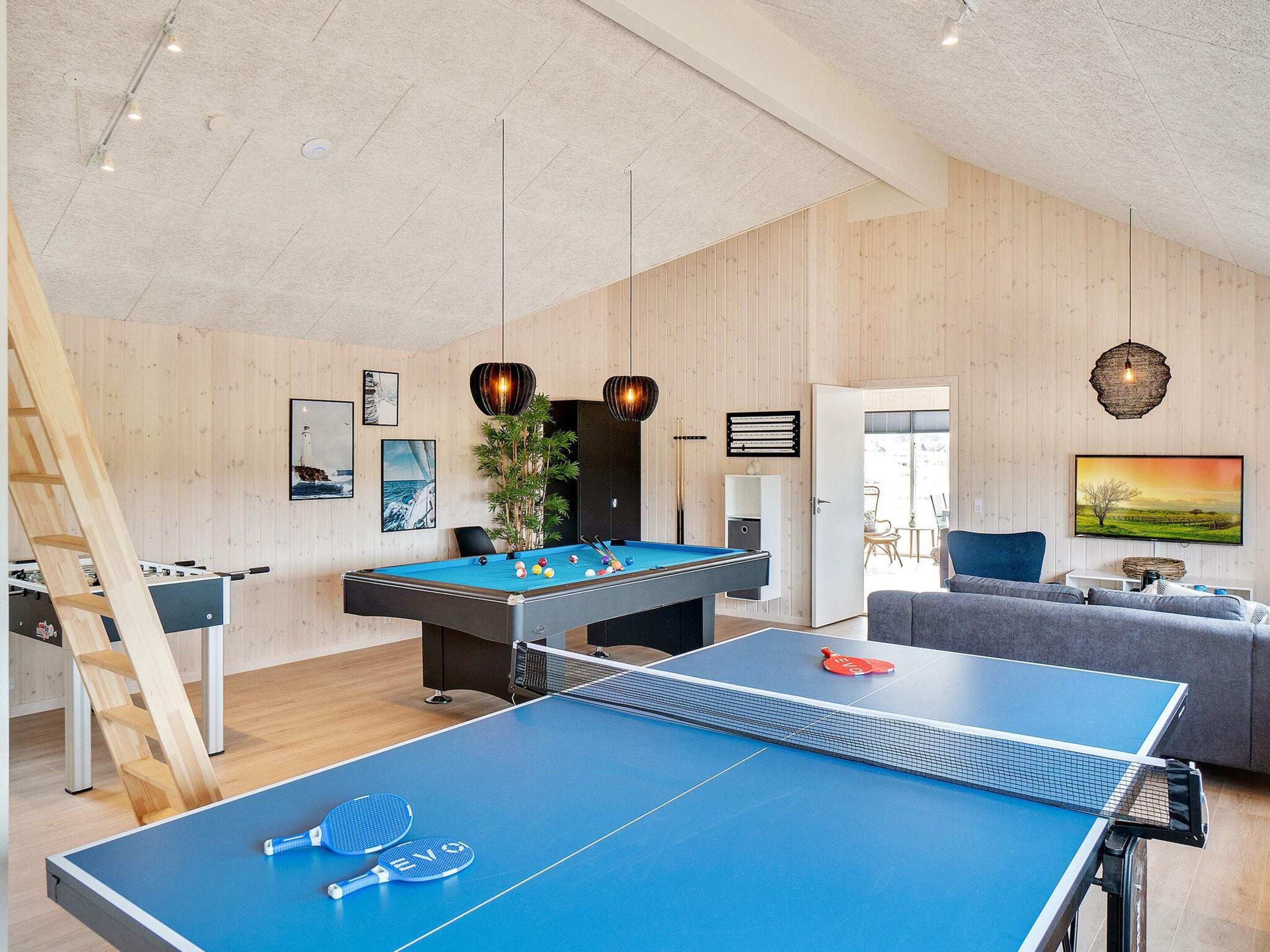 A room with a pool table, a ping pong table, and a foosball table.
