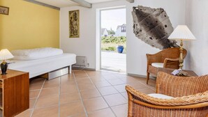Quarto com cama, uma cadeira de vime, luminária e uma grande obra de arte abstrata na parede.