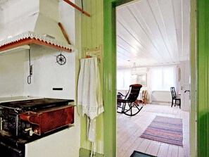 A room with a vintage stove, a rocking chair, and a dining area with a table and chairs.