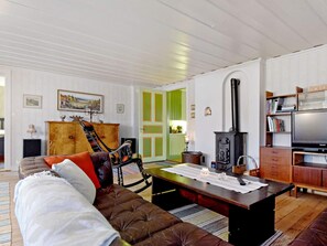 A living room with a sofa, a wooden coffee table, a fireplace, and a television.